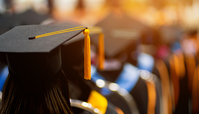 Graduate in cap and gown holding a diploma